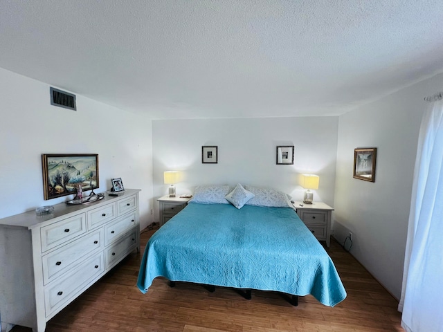 bedroom with dark hardwood / wood-style flooring and a textured ceiling