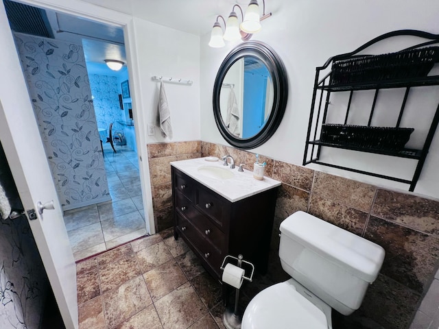 bathroom featuring vanity, tile walls, and toilet