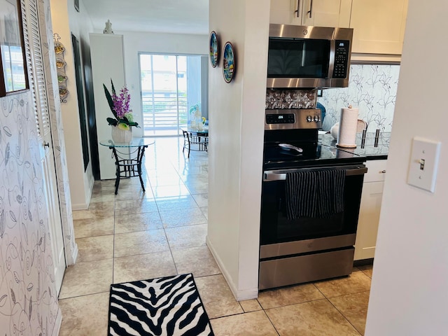 kitchen featuring white cabinets, light tile patterned flooring, stainless steel appliances, and tasteful backsplash