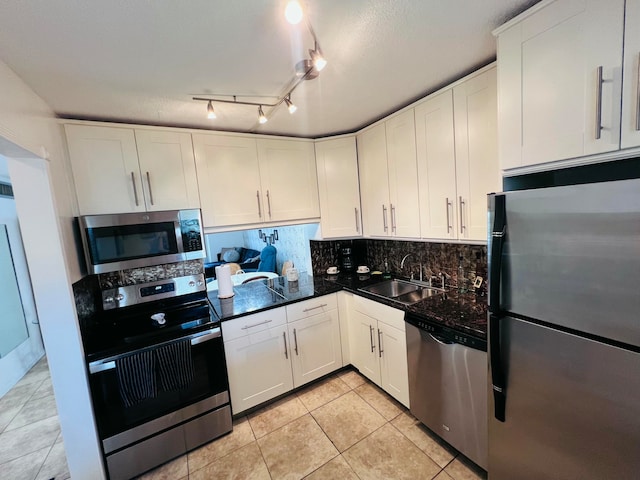 kitchen featuring sink, light tile patterned floors, decorative backsplash, white cabinets, and appliances with stainless steel finishes