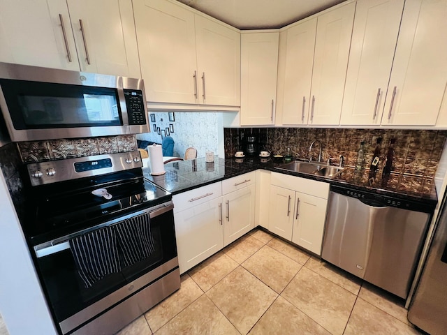 kitchen featuring decorative backsplash, stainless steel appliances, sink, white cabinetry, and light tile patterned flooring