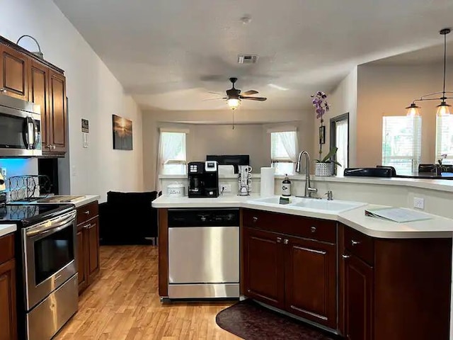 kitchen with ceiling fan, pendant lighting, sink, stainless steel appliances, and light wood-type flooring