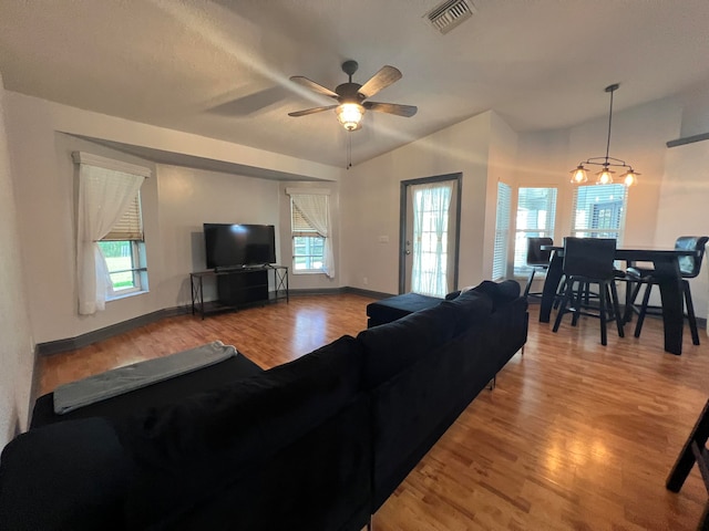 living room with ceiling fan with notable chandelier and hardwood / wood-style floors