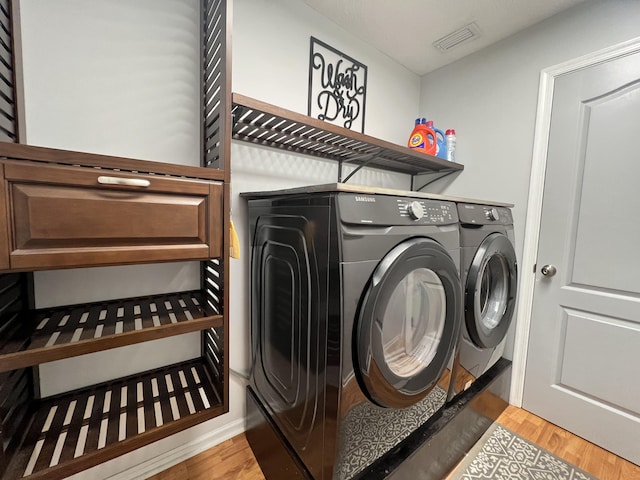 laundry area with light hardwood / wood-style flooring and washer and dryer