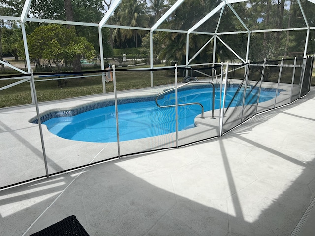 view of swimming pool featuring a patio, a lawn, and a lanai