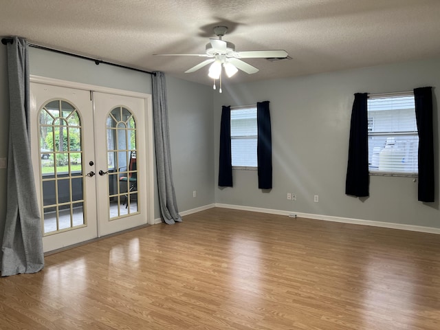 unfurnished room featuring light hardwood / wood-style floors, ceiling fan, french doors, and a textured ceiling