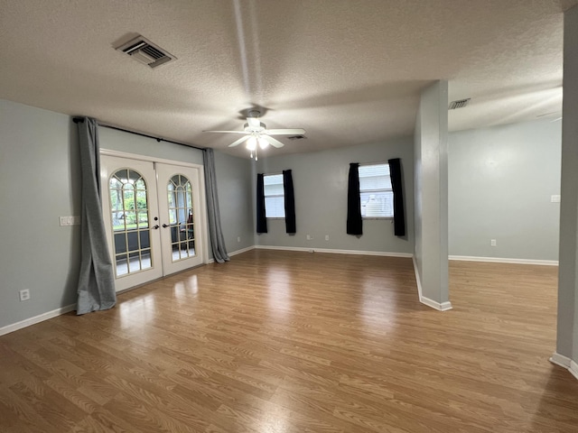 unfurnished room with light wood-type flooring, a textured ceiling, ceiling fan, and french doors