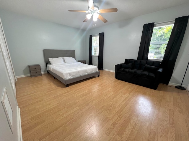 bedroom with multiple windows, light wood-type flooring, and ceiling fan