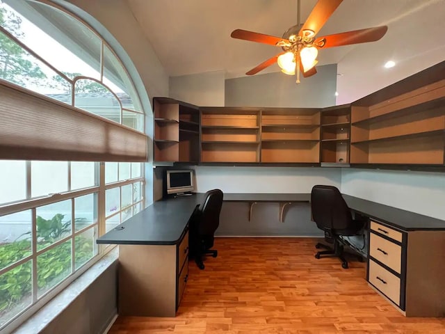 home office with built in desk, ceiling fan, and a healthy amount of sunlight