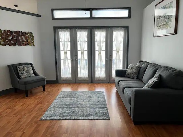 interior space featuring a healthy amount of sunlight, a towering ceiling, hardwood / wood-style floors, and french doors