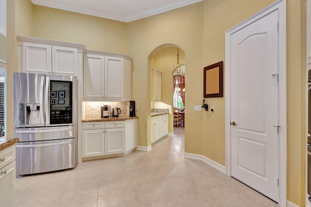 kitchen with light tile patterned flooring, light stone counters, white cabinets, stainless steel appliances, and crown molding