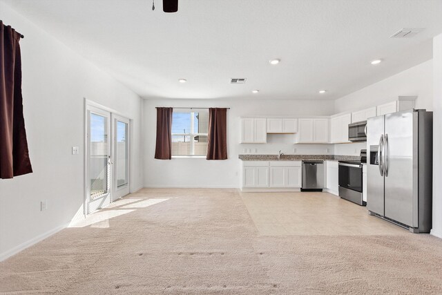 kitchen featuring stainless steel appliances, white cabinets, light colored carpet, and sink