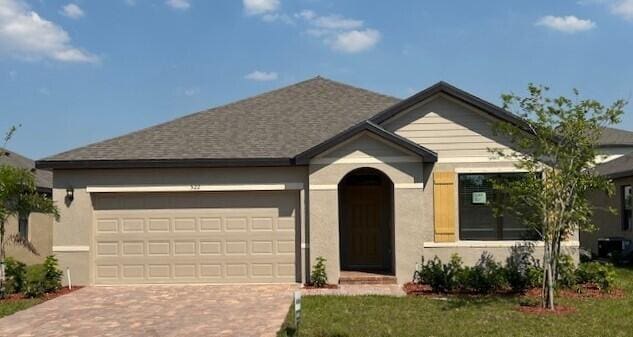view of front of house featuring stucco siding, an attached garage, and decorative driveway