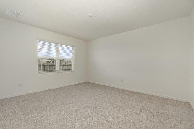 unfurnished room featuring baseboards, a textured ceiling, visible vents, and light colored carpet