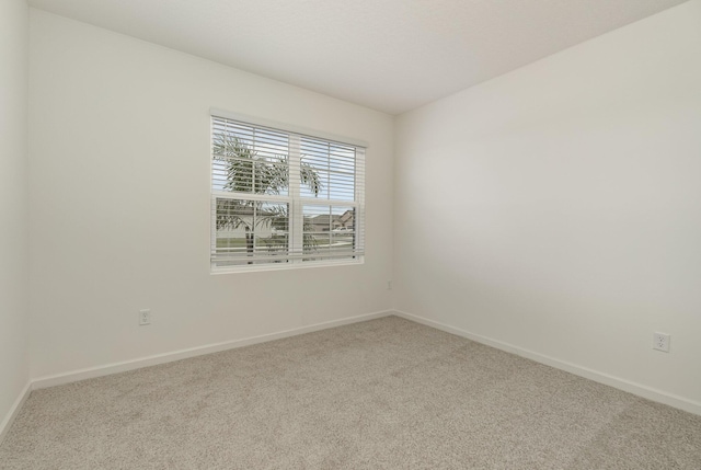 spare room with baseboards and carpet