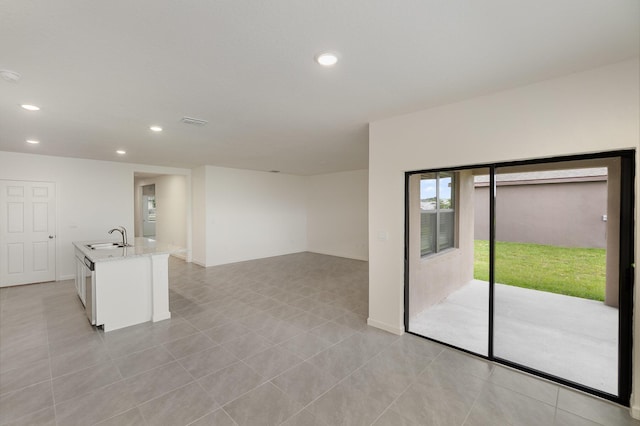 unfurnished room with light tile patterned flooring, visible vents, baseboards, recessed lighting, and a sink