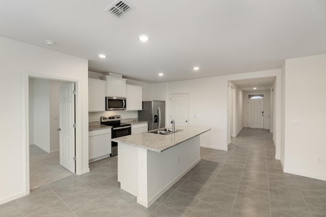 kitchen with a sink, a center island with sink, stainless steel appliances, visible vents, and white cabinets