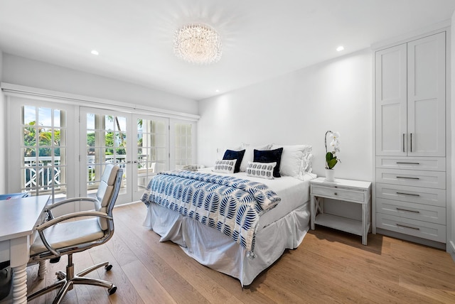 bedroom with access to outside, an inviting chandelier, light hardwood / wood-style flooring, and french doors