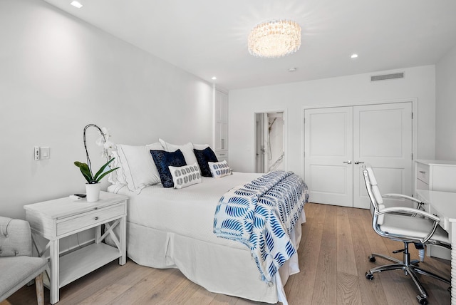 bedroom featuring a closet, a chandelier, and light hardwood / wood-style floors