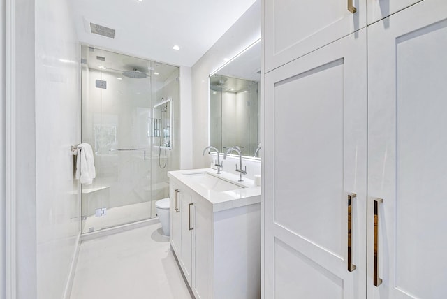 bathroom featuring vanity, toilet, and a shower with door