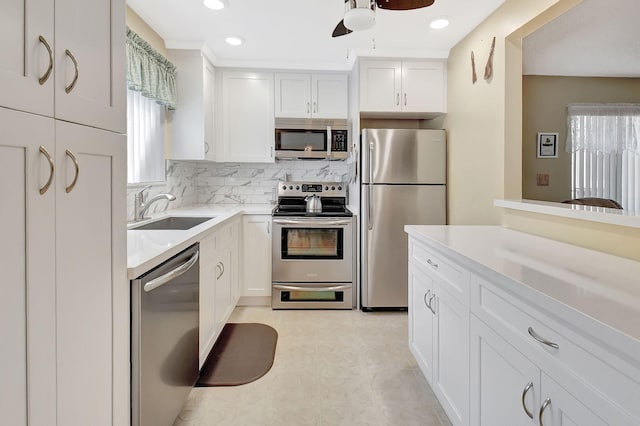 kitchen with decorative backsplash, white cabinets, stainless steel appliances, and a sink