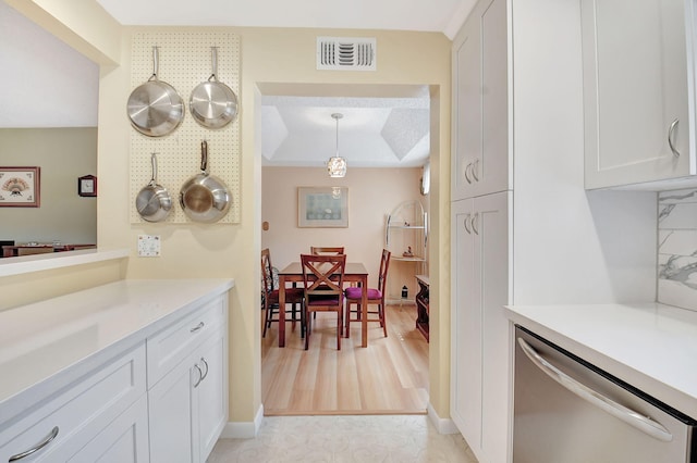 kitchen with visible vents, backsplash, light countertops, white cabinetry, and stainless steel dishwasher