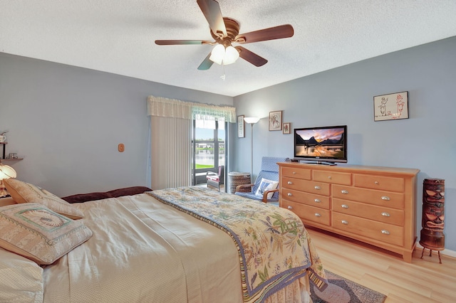 bedroom with a textured ceiling, a ceiling fan, and light wood finished floors