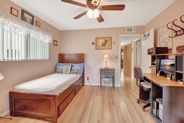 bedroom featuring baseboards, visible vents, light wood-style flooring, ceiling fan, and a textured ceiling