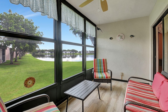 sunroom with ceiling fan and a water view