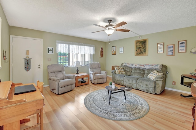 living area with a ceiling fan, wood finished floors, baseboards, and a textured ceiling