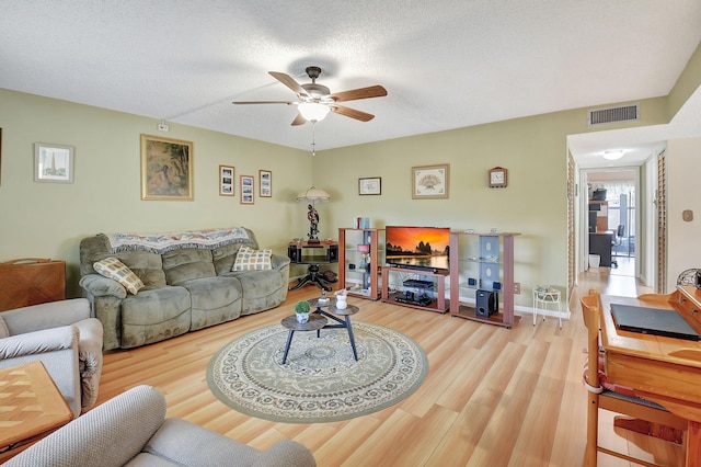 living area with visible vents, a textured ceiling, wood finished floors, and a ceiling fan