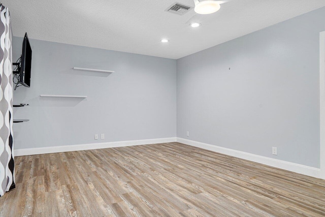 empty room with light hardwood / wood-style floors and a textured ceiling