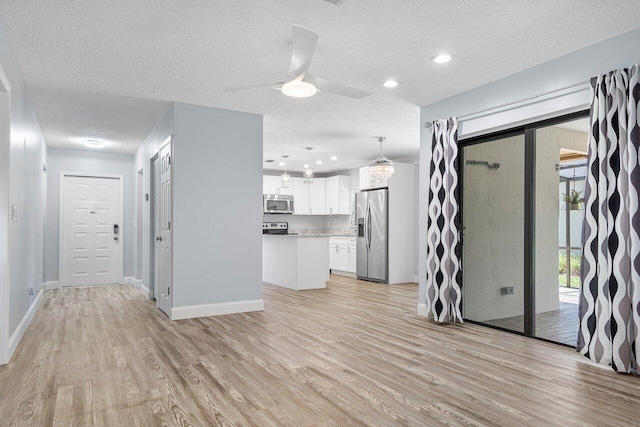 interior space featuring a textured ceiling, light hardwood / wood-style floors, and ceiling fan