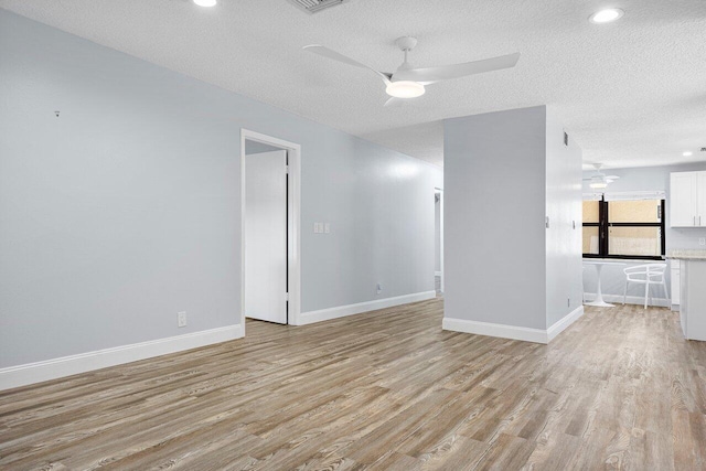 spare room featuring light wood-type flooring, a textured ceiling, and ceiling fan