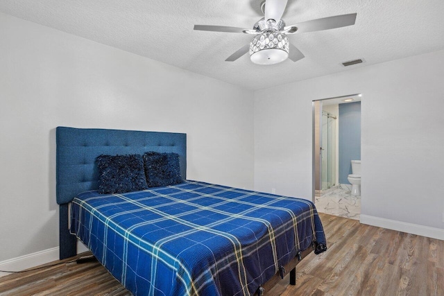 bedroom with ceiling fan, hardwood / wood-style flooring, connected bathroom, and a textured ceiling