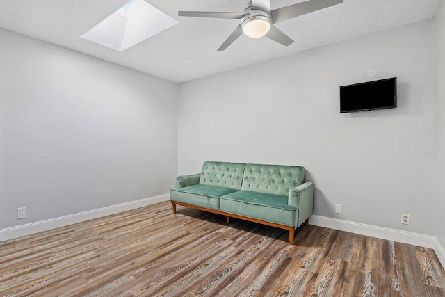 sitting room with ceiling fan, a skylight, a textured ceiling, and hardwood / wood-style flooring