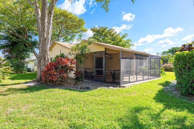 rear view of house featuring a yard and a sunroom