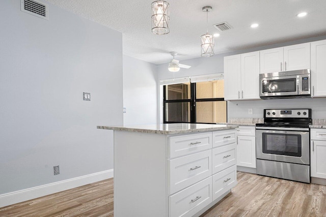 kitchen with white cabinets, a kitchen island, stainless steel appliances, light wood-type flooring, and ceiling fan