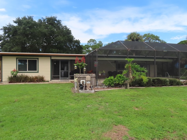 back of property featuring glass enclosure and a yard