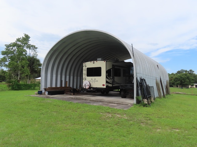 view of outdoor structure featuring a lawn and a carport