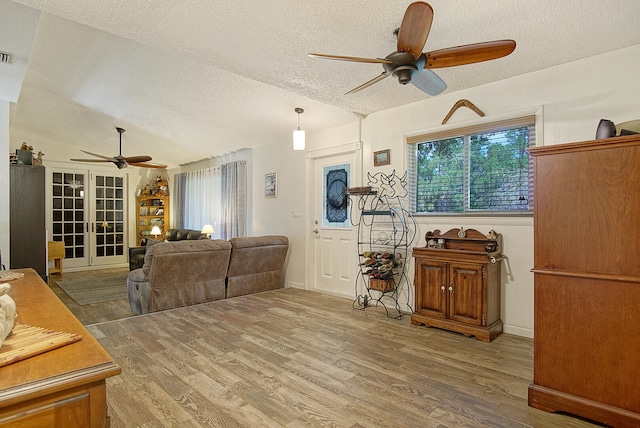 living room featuring wood-type flooring, ceiling fan, and a textured ceiling