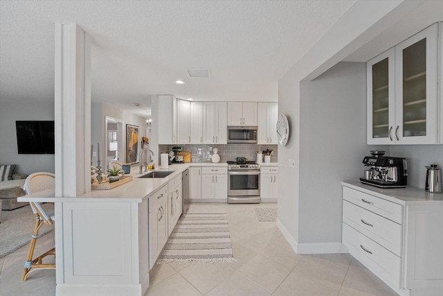 kitchen with white cabinetry, sink, light tile patterned floors, and stainless steel appliances