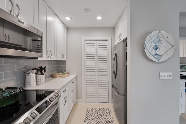 kitchen featuring decorative backsplash, light stone countertops, appliances with stainless steel finishes, light tile patterned flooring, and white cabinetry