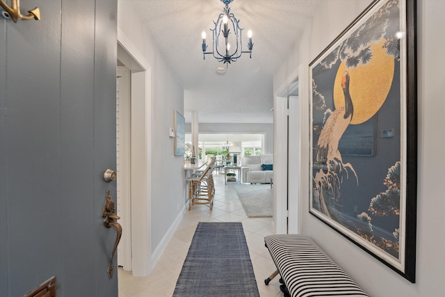 corridor with light tile patterned floors, a textured ceiling, and a notable chandelier