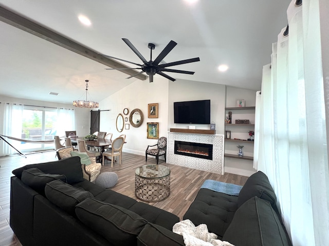 living room featuring ceiling fan with notable chandelier, a fireplace, lofted ceiling with beams, and hardwood / wood-style flooring