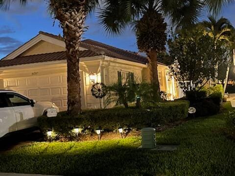 property exterior at dusk featuring a garage and a yard