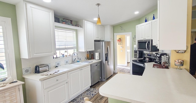 kitchen with white cabinets, hanging light fixtures, dark hardwood / wood-style floors, and appliances with stainless steel finishes