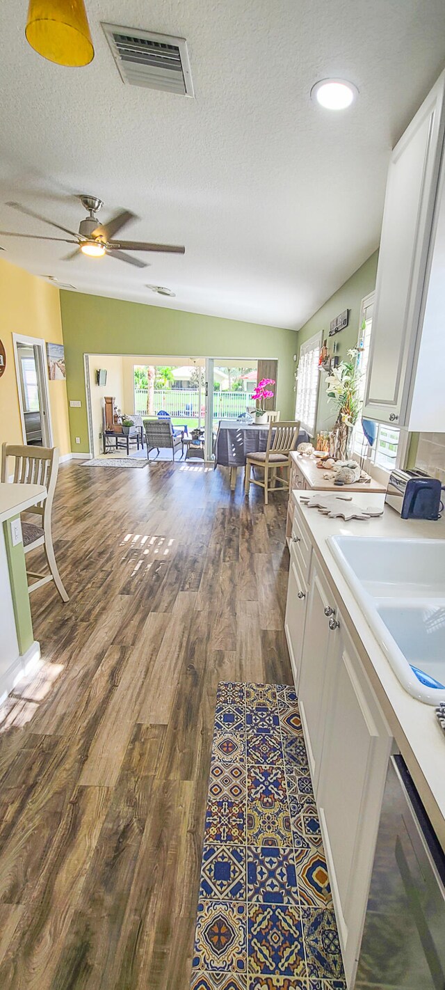 kitchen with white cabinets, dark hardwood / wood-style floors, vaulted ceiling, and sink