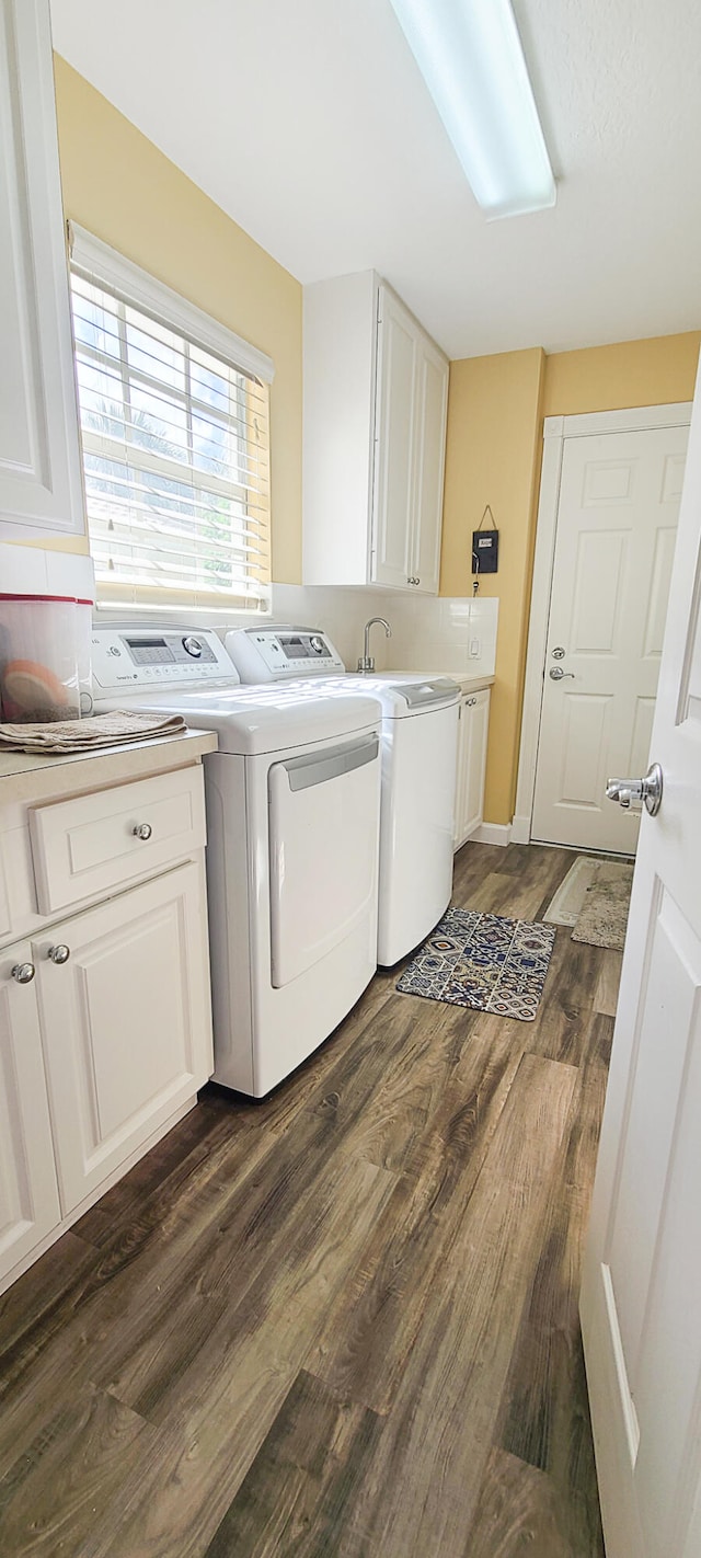 laundry area featuring cabinets, dark hardwood / wood-style floors, and washing machine and clothes dryer