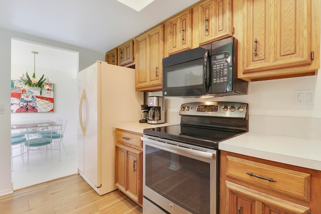 kitchen with stainless steel electric stove, light wood-type flooring, and white fridge